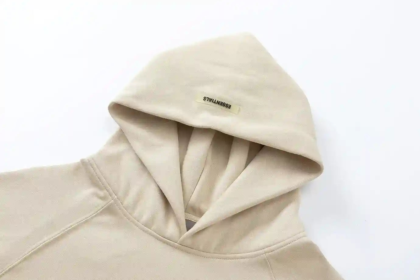 Close-up of light cream fleece texture and rubberized Essentials Black Bar detail