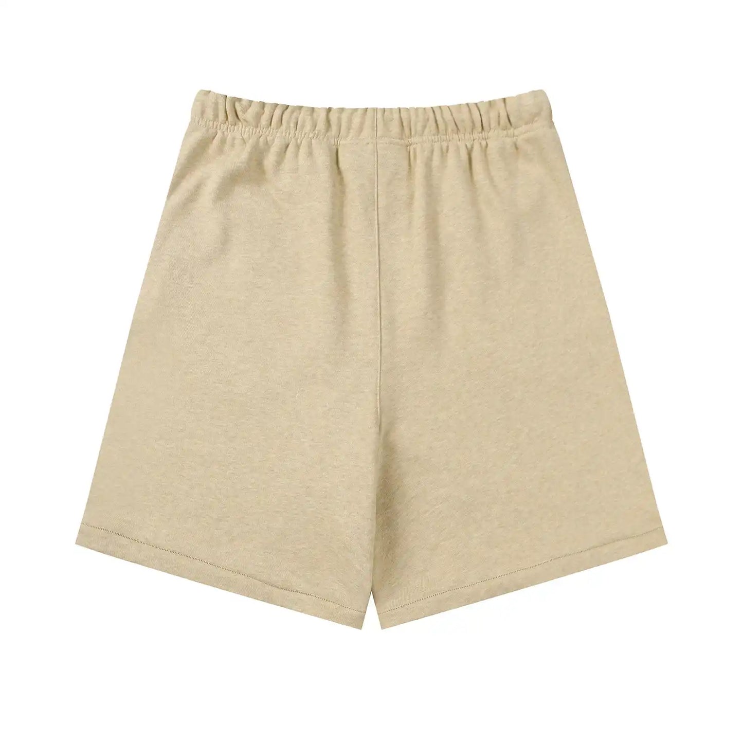Fear of God Essentials Calm Shell beige shorts, front view, showing a relaxed fit with an elastic waistband and subtle “ESSENTIALS Fear of God” logo detailing