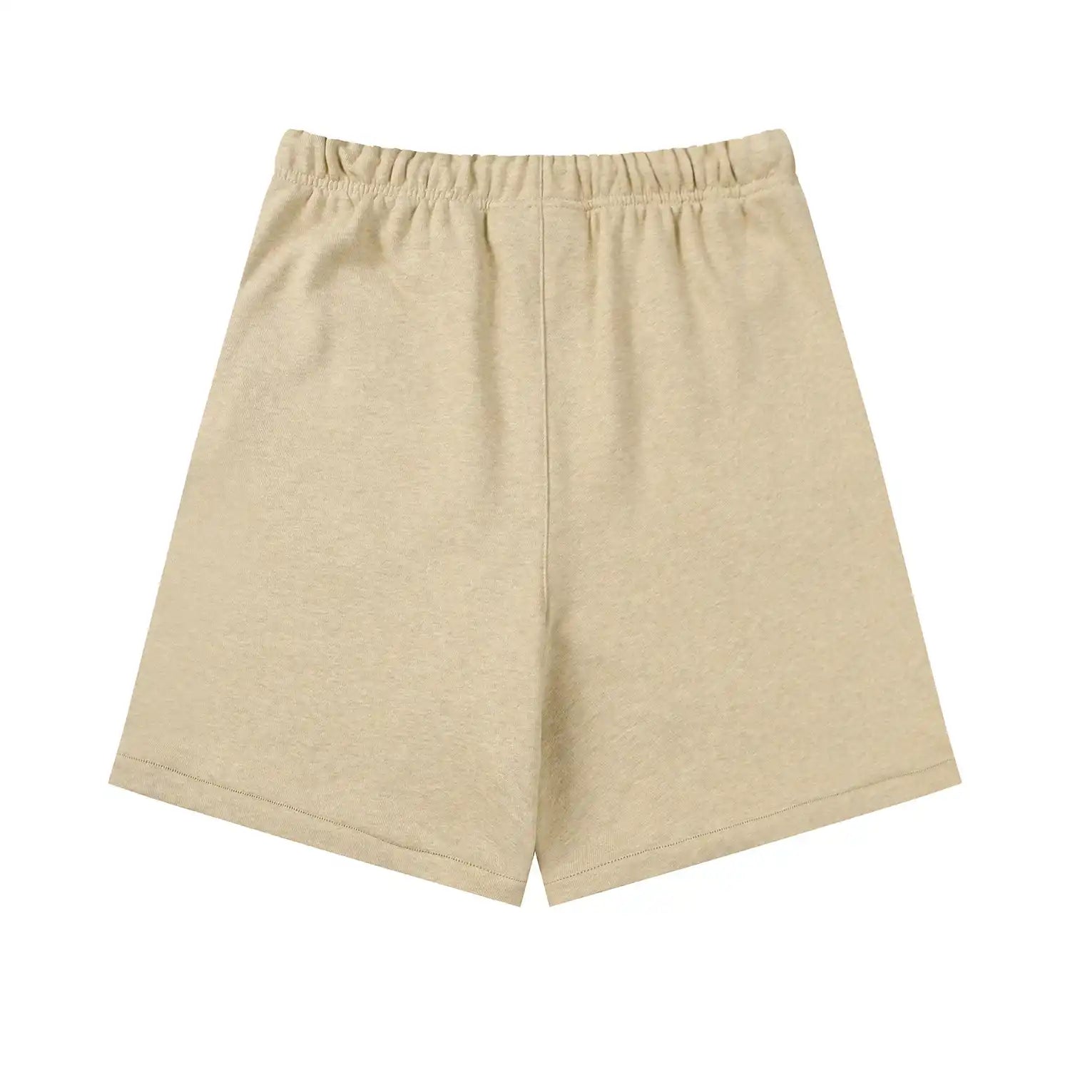 Fear of God Essentials Calm Shell beige shorts, front view, showing a relaxed fit with an elastic waistband and subtle “ESSENTIALS Fear of God” logo detailing