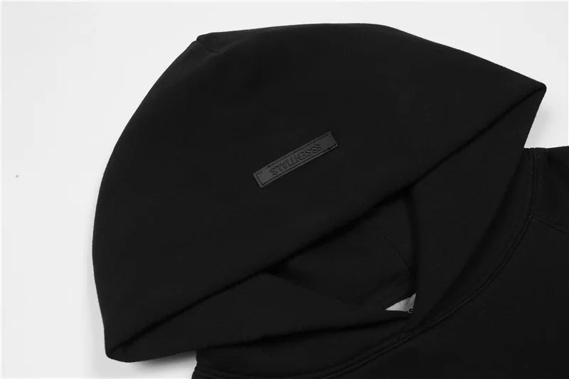 Close-up of Essentials black hoodie fleece texture and rubberized front bar logo
