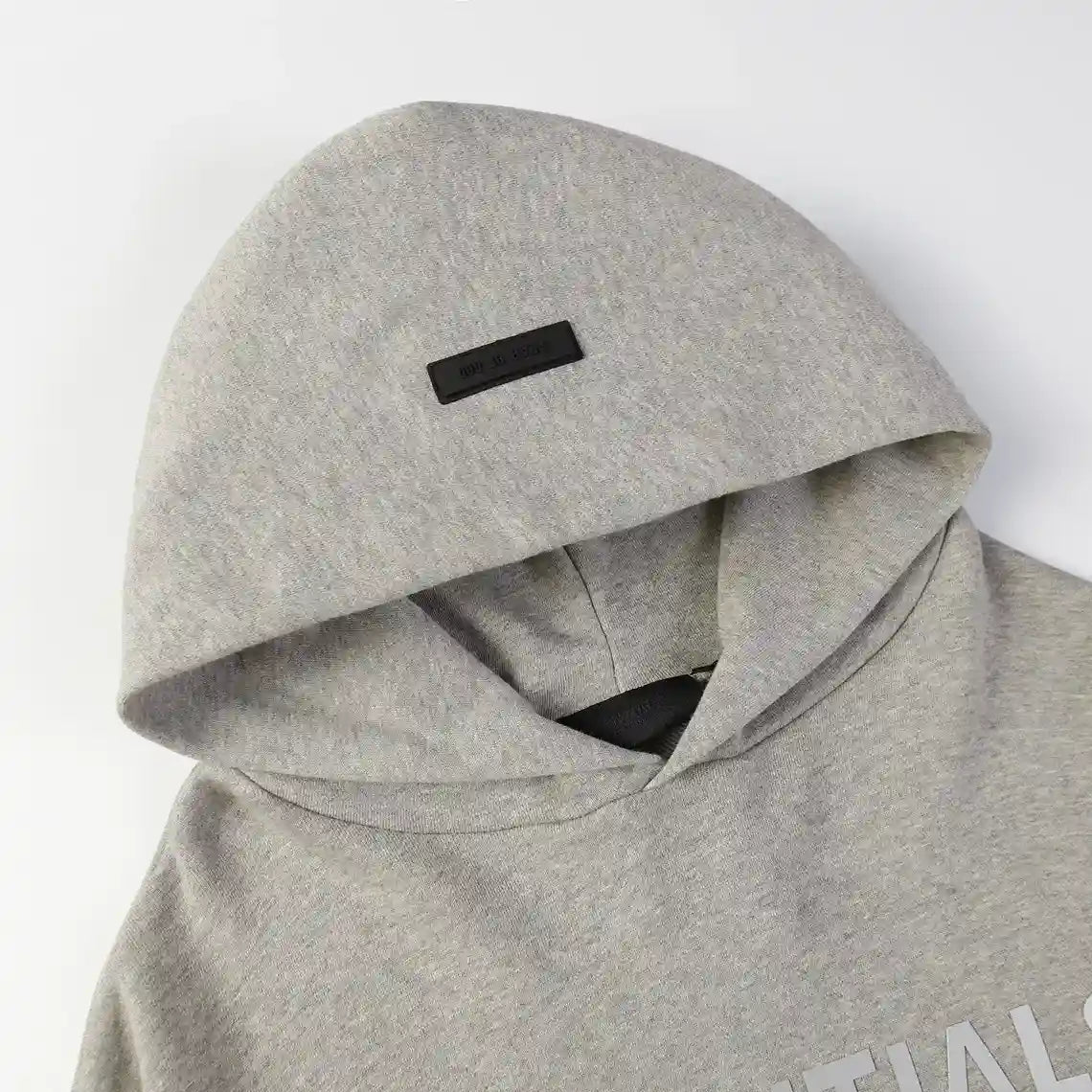 Close-up of dark heather oatmeal fleece texture and rubberized Essentials logo bar